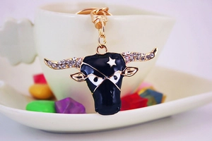 Close-up of golden bull head keychain with white rhinestones and black enamel detail