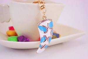 Detail of a white horn-shaped keychain with sky blue floral patterns and shiny rhinestones