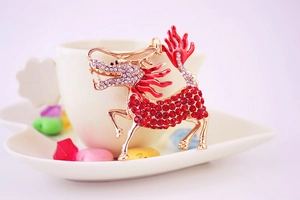Detail of red and gold kirin keychain with rhinestones hanging on a coffee cup