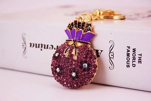 Detail of money bag keychain with purple rhinestones and gold plating on a book