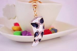 Close-up of a creative horn-shaped keychain with white enamel and sparkling rhinestones