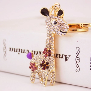 Sparkling crystal giraffe keychain with purple rhinestones on a white book prop