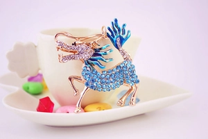 Detailed view of mythical dragon pendant with blue rhinestones and gold enamel finish