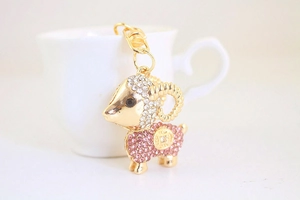 Dettaglio portachiavi a forma di capra con strass rosa e bianchi su tazza di porcellana bianca