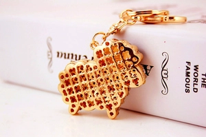 Detailed close-up of a gold-plated sheep keychain featuring an openwork clover pattern