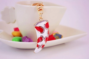 Close-up of golden horn pendant keychain with white enamel and red crystal details