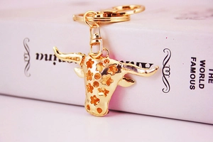 Golden bull head keychain with hollow star details hanging on a white book spine