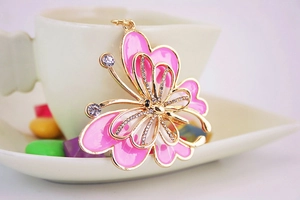 Détail du porte-clés papillon avec des ailes en émail rose et des strass brillants