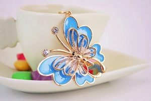 Détail d'un porte-clés papillon en émail bleu orné de strass sur une tasse en céramique