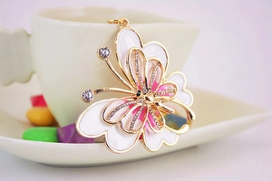 Détail d'un pendentif papillon en émail blanc et zircons brillants sur métal doré