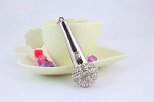 Macro shot of silver microphone keychain featuring white rhinestones on a white cup