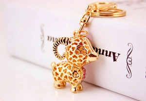 Detail view of a gold-plated goat keychain featuring pink crystal inlays and镂空 patterns