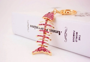 Detailed close-up of crystal fish bone keychain with pink rhinestones on a book
