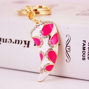 Elegant gold horn keychain with white enamel and pink accents on a white book