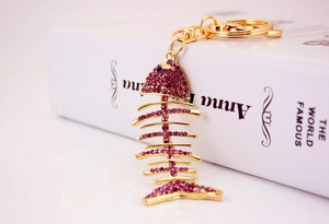 Close-up of golden fishbone keychain with purple crystals and lobster clasp detail