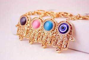Detailansicht goldener Hamsa-Hand-Anhänger mit Strasssteinen und Böse-Blick-Perlen