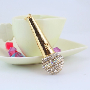 Golden microphone keychain with sparkling rhinestones on a white ceramic cup edge