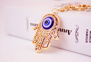 Makroansicht goldener Hamsa-Hand Schlüsselanhänger mit blauem Auge und Kristallen