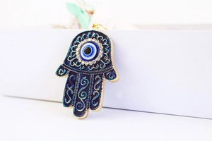 Macro shot of blue enamel Hamsa Hand pendant with Evil Eye and sparkling crystals