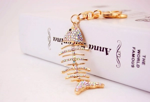 Close-up of golden fishbone keychain with rainbow crystals and lobster clasp on a book
