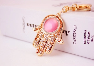 Detaillierte Nahaufnahme der goldenen Hand der Fatima mit rosa Opal und Kristallakzenten
