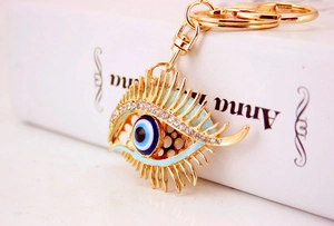 Detail of a sparkling evil eye keychain with rhinestones and lashes on a book background