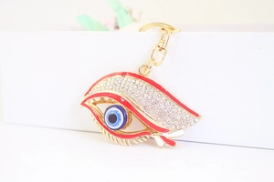 Détail du porte-clés œil maléfique en émail rouge avec strass brillants et finition dorée