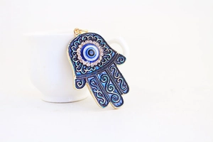 Detail shot of a blue Hamsa hand pendant with evil eye and sparkling crystals