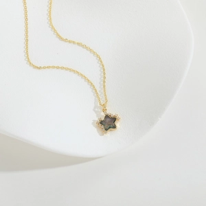 Detail of gold star necklace with dark iridescent core and shimmering crystal edges