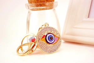 Macro detail of gold evil eye keychain with blue enamel and sparkling rhinestones