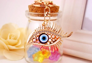 Detailed close-up of golden evil eye keychain with rhinestones on an eyelash design