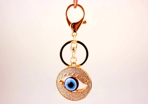 Macro view of gold-plated Evil Eye keychain with crystal pave and blue core details