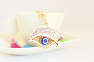 Détail du porte-clés œil maléfique avec perle bleue et strass accroché sur une tasse