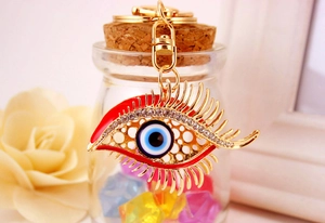 Detail of red rhinestone Evil Eye keychain with gold finish on a decorative glass bottle
