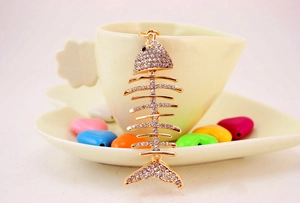 Macro detail of a crystal-encrusted fishbone keychain with sparkling rhinestones and gold plating