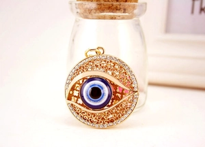 Détail d'un pendentif œil bleu doré avec strass scintillants et motifs ajourés élégants