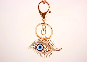 Detailed close-up of golden Evil Eye keychain with sparkling rhinestones and long eyelashes