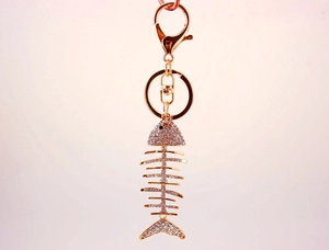 Detailed close-up of golden fishbone keychain with sparkling crystal rhinestones and lobster clasp