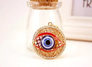 Vue macro du porte-clés œil bleu doré avec émail rouge et strass étincelants