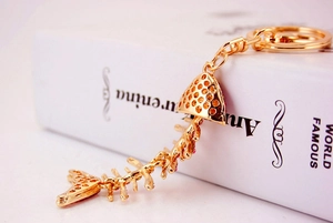 Detail of pink rhinestone fishbone keychain with gold-tone lobster clasp on white book