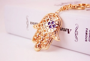 Detailaufnahme Hamsa-Hand Schlüsselanhänger in Gold mit Kleeblattmuster und blauem Auge