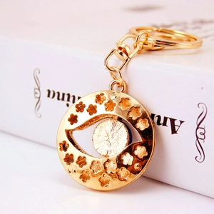 Golden Evil Eye keychain with floral hollow design and crystal accents on white book