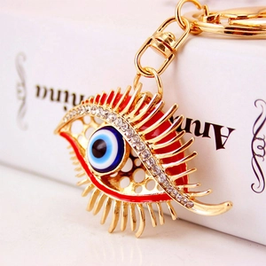 Golden evil eye keychain with sparkling rhinestones and eyelashes on a white book
