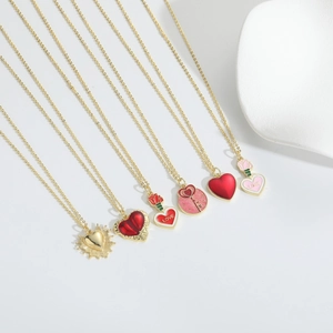 Detail view of six heart-shaped pendants with red drip oil finish and gold chains