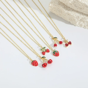 Dettaglio di pendenti a forma di fragola e ciliegia su collane dorate eleganti