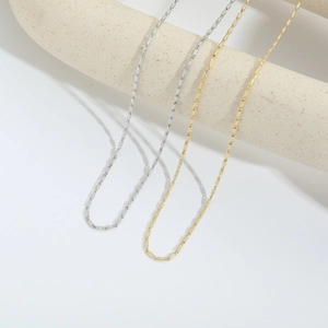 Minimalist 14k gold and silver dainty link chains displayed on a ceramic stand