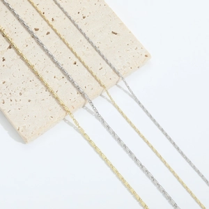 Minimalist 14k gold and silver plated chain necklaces on a modern stone display