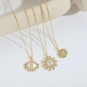 Three gold religious necklaces with Virgin Mary pendants and pearl cross on stone stand