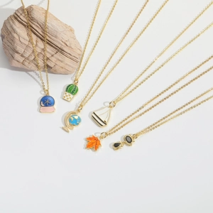 Detail view of six diverse enamel charms including cactus and globe on gold chains