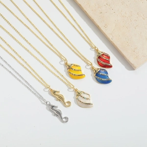 Detailed shot of seahorse and shell pendants with colorful enamel and zircon inlay